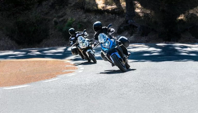 Actiefoto van twee motorrijders op een CF Moto 650 MT waarvan beide met koffers uitgerust in heuvelachtig landschap