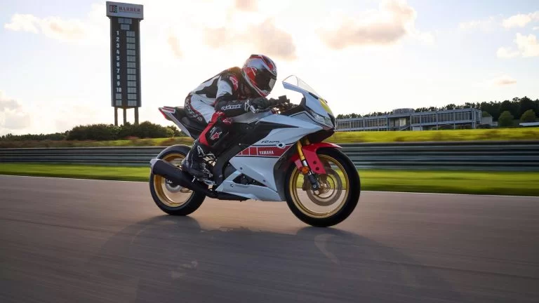 wit met rode Yamaha YZF-R125 World GP 60th Anniversary rijd op een circuit te zien vanuit het zijaanzicht