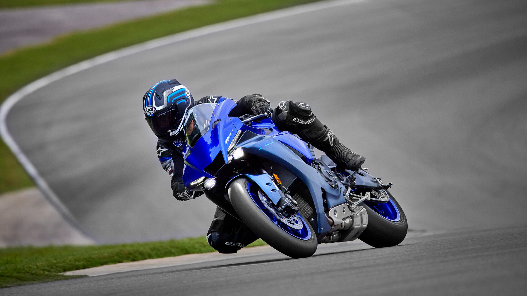 blauwe Yamaha R1 rijdend door een bocht over een circuit te zien vanuit het voorzijaanzicht