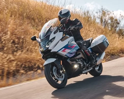 actiefoto van motorrijder op een bmw k1600 gt die door langs tarweheuvels rijdt