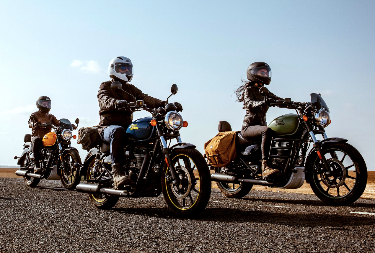 3 royal enfields meteor 350 met motorrijders op een verlaten weg