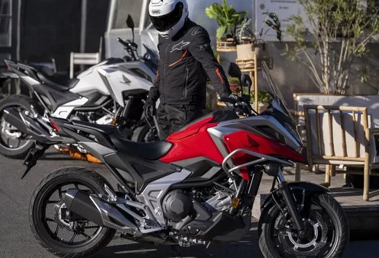 foto van motorrijder die bij de nieuwe rode honda nc750x uit 2023 staat