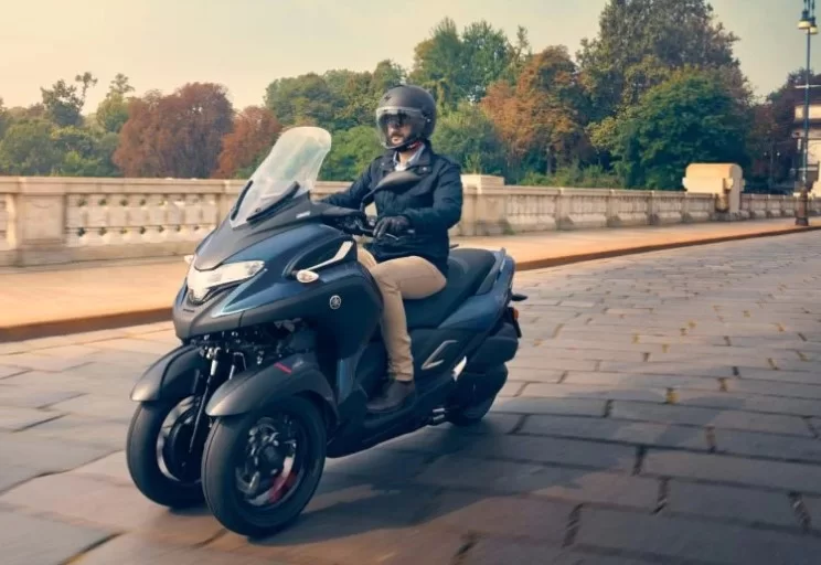 actiefoto van mototrijder op een brug met een 2023-yamaha-tricity-motorscooter-driewieler