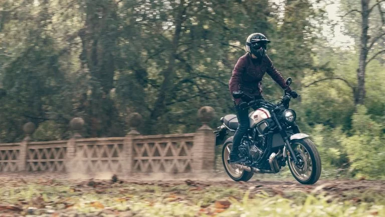 Motorrijder rijdt op een sport Heritage motor over een onverharde weg