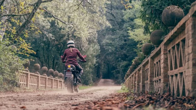 motorrijdster rijdt over een onverharde weg op een sport Heritage motor