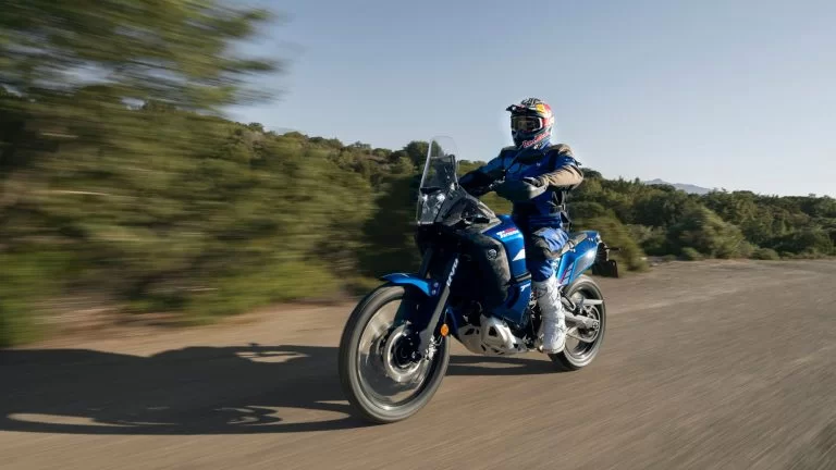 motorrijder rijdt op een blauwe adventure motor over een zandpad
