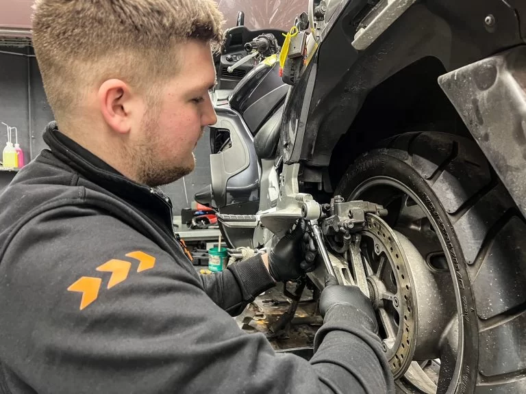 Monteur in werkplaats die motoronderhoud aan het uitvoeren is