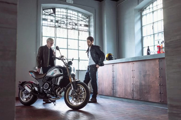 Lifestylefoto CF Moto 700CL-X Heritage van twee heren in een ruimte met grote ramen en een balie