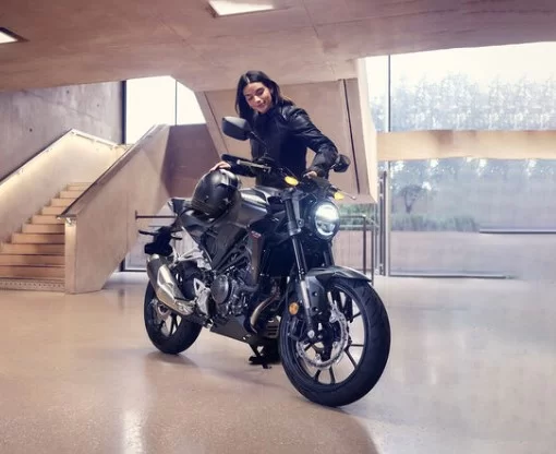 Vrouw die op het punt staat op een zwarte Honda cb300f te stappen