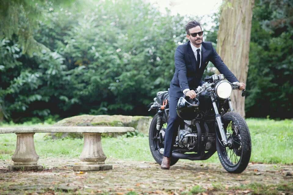 man in pak op een cafe racer in park