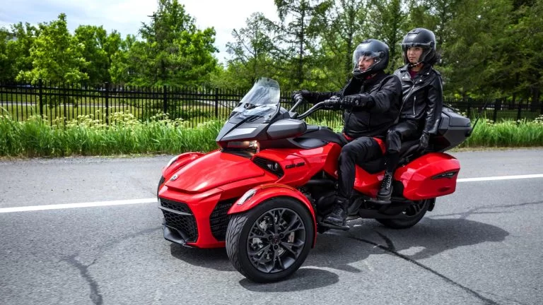 Actiefoto rode 2022 Can-Am Spyder F3 Limited Special Series met rijder en passagier door bosrijke omgeving