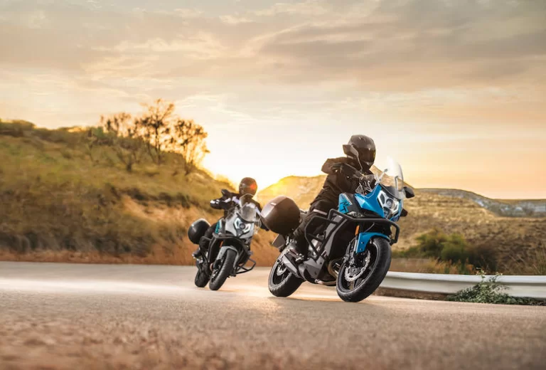 Actiefoto van twee motorrijders op een CF Moto 650 MT waarvan beide met koffers uitgerust in heuvelachtig landschap