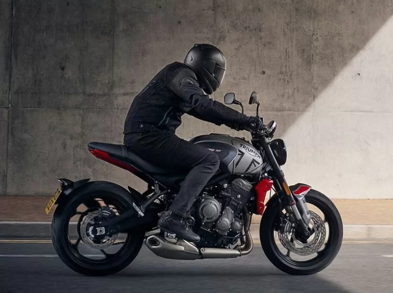 Motorrijder op een triumph trident 660 naked bike die onder een viaduct rijdt