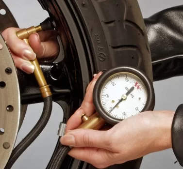 close up van iemand die bandendruk meet van motorfiets