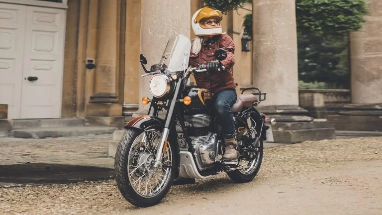 Model op Royal Enfield Classic 350 rijdend langs historisch pand