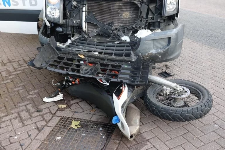 Ongeluk motorrijder en gemeente voertuig. Schade motor en auto