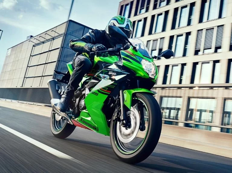 Ninja 125 rijdend over straat met gebouwen op de achtergrond