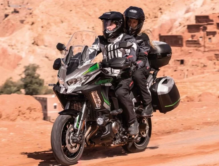 Kawasaki tourmotor met rijder en passagier met bergen