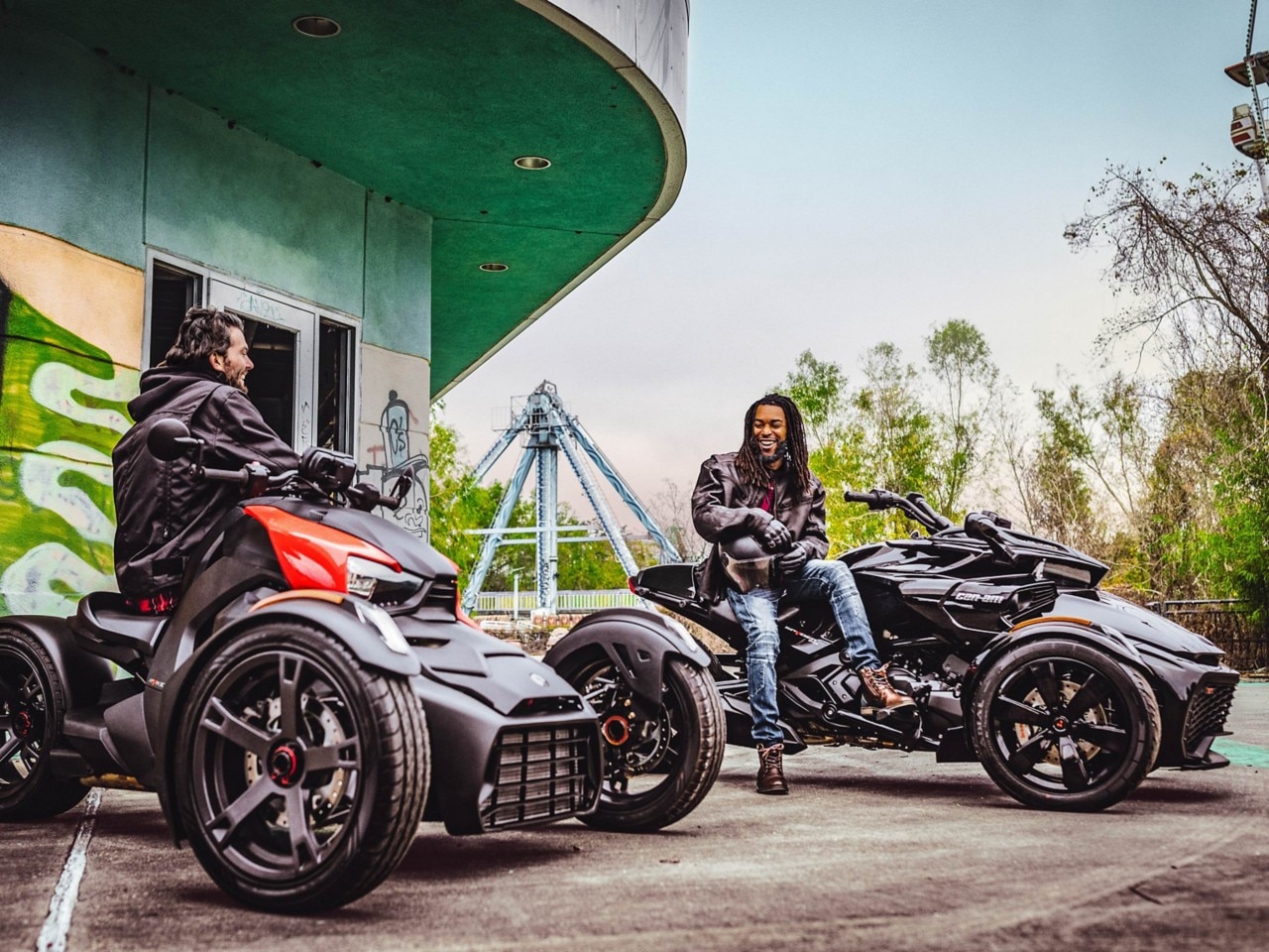 rode en zwarte Can-Am Ryker 600 te zien vanuit het voorzijaanzicht geparkeerd naast een groen gebouw
