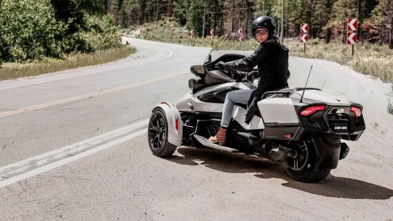 witte Can-Am spyder rt staat met rijder naast de weg in een bosrijke omgeving