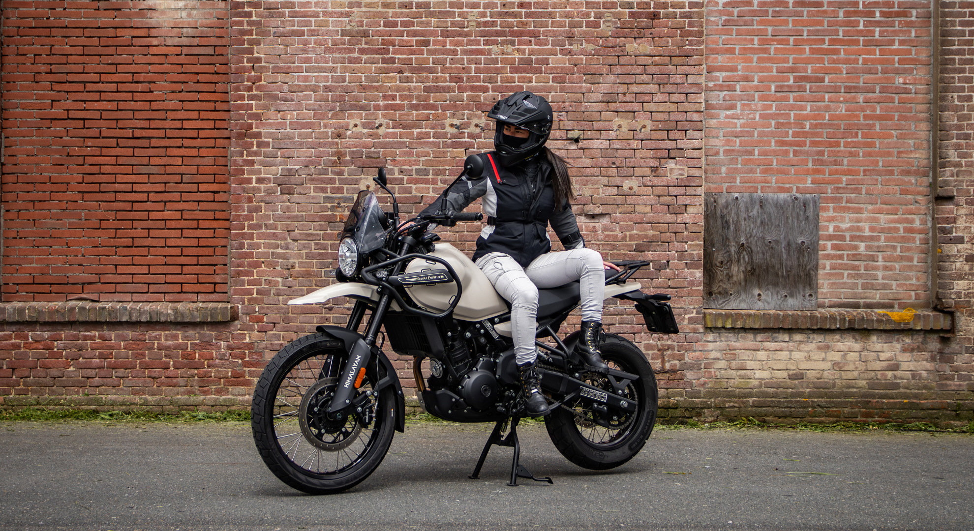 Royal Enfield Himalaya met rijder. Stilstaand voor een pand.