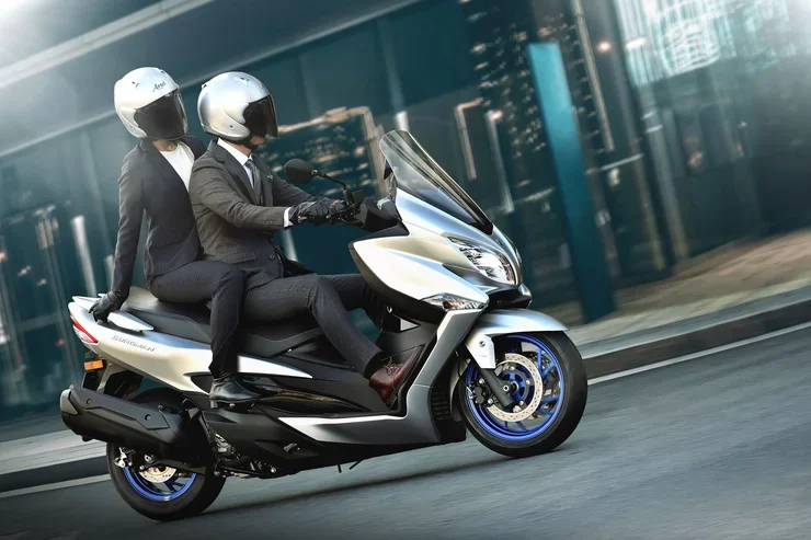 Suzuki motorscooter rijdend over straat.